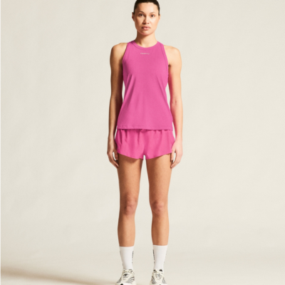 Craft Essential Mesh Singl in Pink, aus atmungsaktivem Material, präsentiert sich mit schmalem Schnitt und Rundhalsausschnitt, ideal für sportliche Aktivitäten. Gezeigt wird das Top zusammen mit einer passenden Hose.