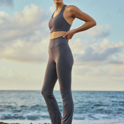 Die Legacy Flare High Waist Tight von Röhnisch in grauer Farbe, aus dehnbarem Material, hat einen hohen Taillenbund und einen figurbetonten Schnitt, ideal für sportliche Aktivitäten am Strand.