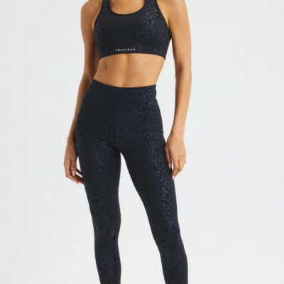 Die Leo Emboss High Waist Tight von Röhnisch in Schwarz besteht aus elastischem Material mit einem eingeprägten Muster. Die Hose hat einen hohen Bund und passt gut zu einem sportlichen Outfit.