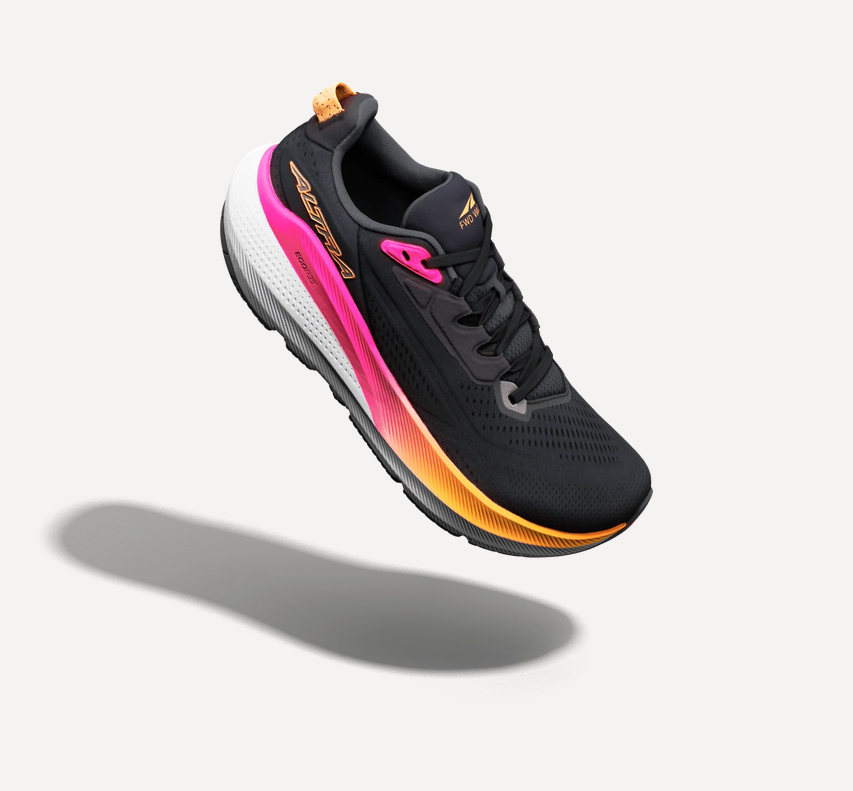 Altra FWD Via 2 Laufschuh in Schwarz mit pink-orangefarbener Zwischensohle, weißer Ferse und schwarzem Obermaterial, schwebend vor hellem Hintergrund mit weichem Schatten.