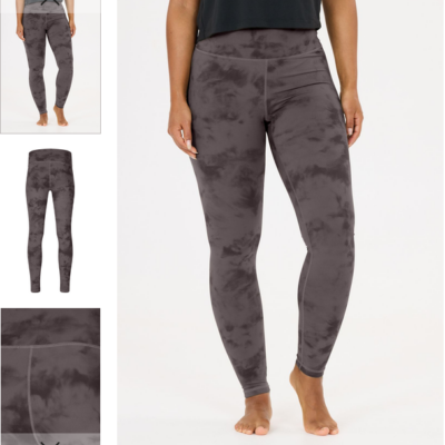 Athlecia Ashanti tights in purple tie-dye polyester, shown on a model standing barefoot against a white background, with a high waist and ankle-length fit.